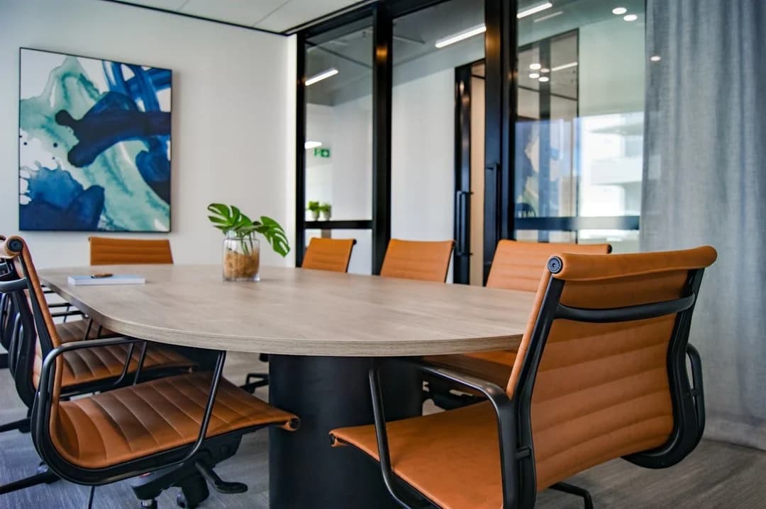 A meeting room with a long timber table and orange leather chairs
