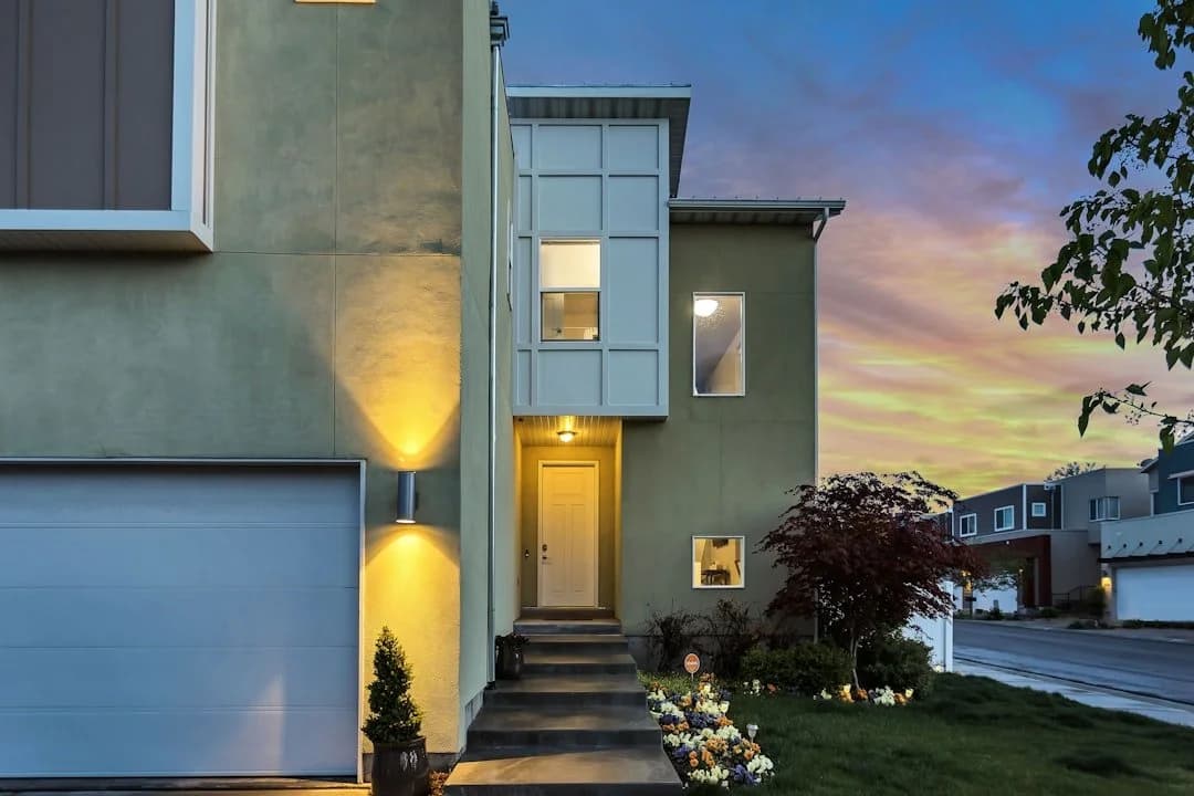 A modern two-storey home at dusk with the front entrance lit up